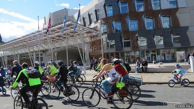 Cyclist ride past the Scottish parliament