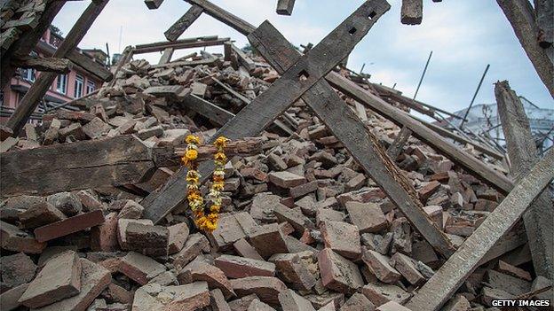 Flowers are left by survivors on top of debris from a collapsed building at Basantapur Durbar Square following an earthquake on 25 April 2015 in Kathmandu, Nepal