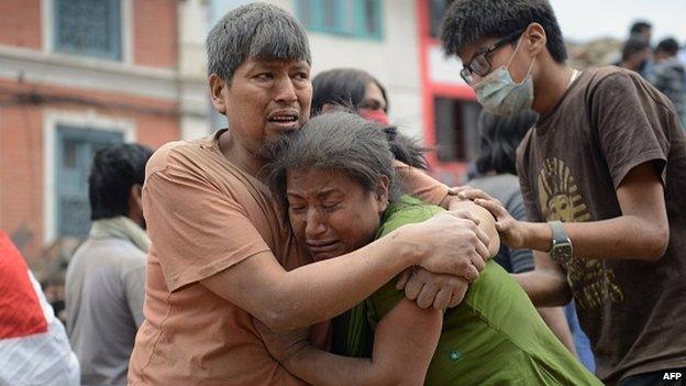 A Nepalese man and woman embrace in Kathmandu's Durbar Square, a Unesco World Heritage Site that was severely damaged by an earthquake on 25 April 2015