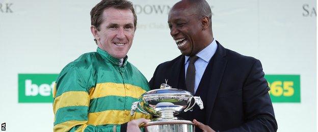 AP McCoy is presented with the jockey's championship trophy by Ian Wright