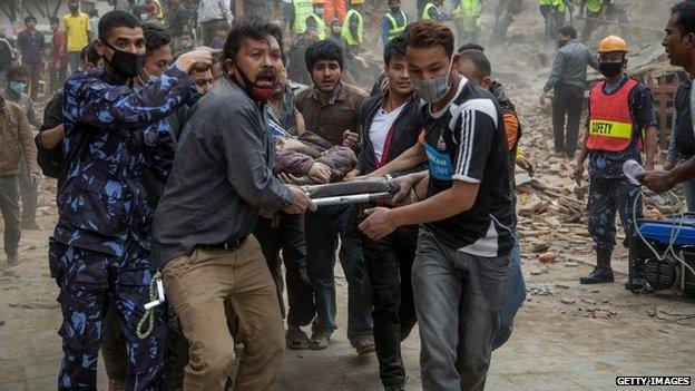 Emergency rescue workers carry a quake victim on a stretcher after Dharara tower collapsed in Kathmandu (25 April 2015)