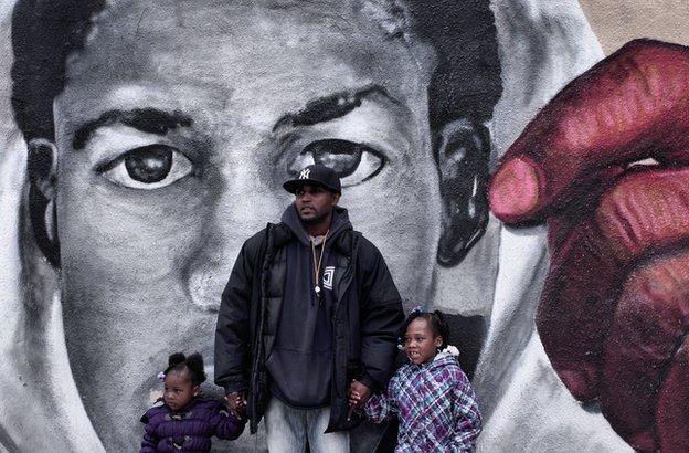 man and daughters in front of trayvon martin mural.