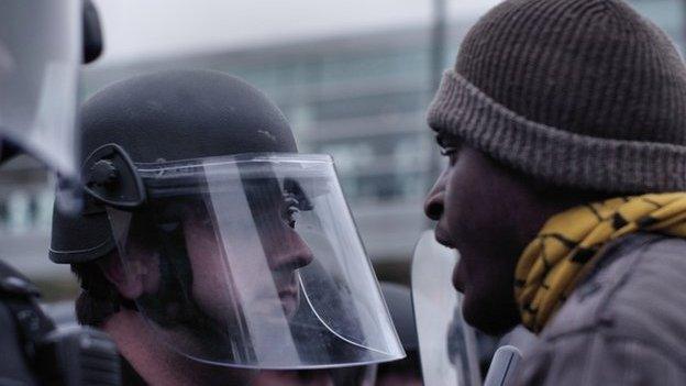 Protestor in the face of a police officer.