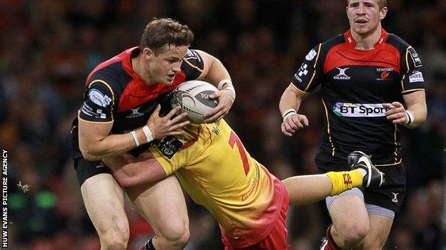 Dragons back Hallam Amos is tackled by Scarlets flanker James Davies during their 'Judgement Day' match at the Millennium Stadium