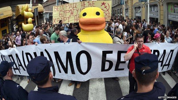 Residents march behind a banner saying "Let us not drown Belgrade"