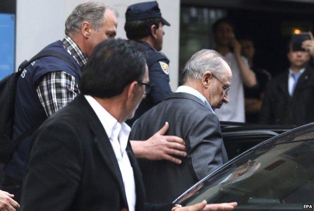 Rodrigo Rato (R) being escorted into a car by Spanish authorities