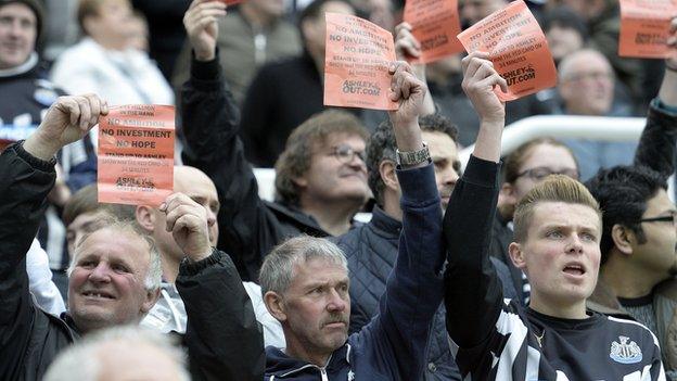 Newcastle United fans hold up signs