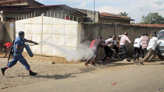 A Burundian riot policeman sprays tear gas on opposition protesters in the capital Bujumbura, Burundi Monday, April 27, 2015