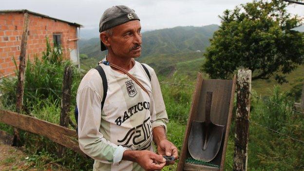 A man holds up small grains of gold in Anori