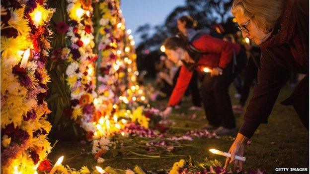 A woman puts flowers on a tribute wall in Sydney for Andrew Chan and Myuran Sukumaran