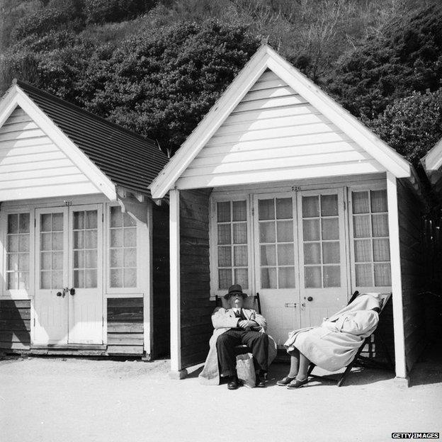 An elderly couple sit outside their beach hut at Bournemouth, circa 1952