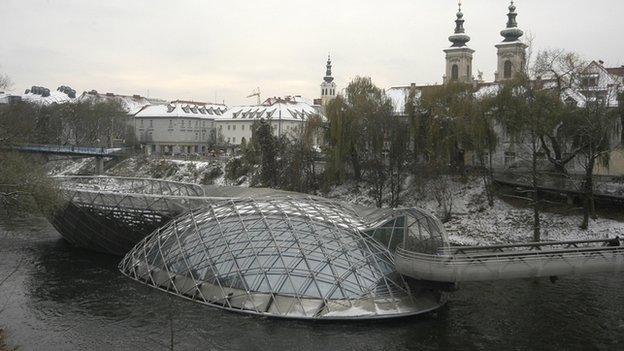 A modern design sits in the middle of the fast flowing River Mur