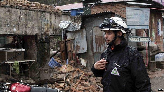 A team member from the British charity Search and Rescue Assistance in Disasters SARAID passes a collapsed building in Sundarijal, Nepal, on 28 April 2015
