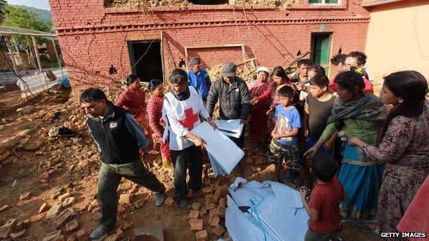 Members of The Nepal Red Cross distribute tarpaulins to displaced residents in Kathmandu