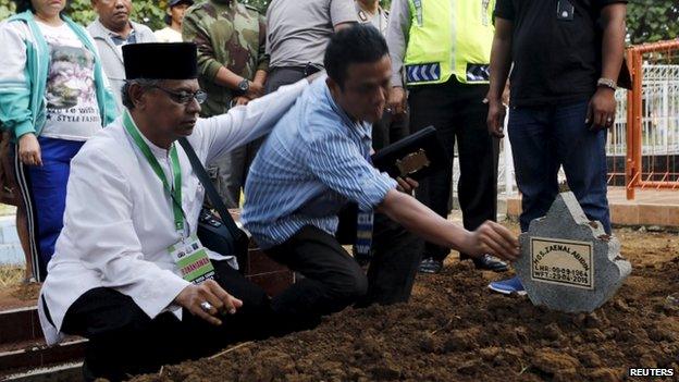 An Islamic cleric (L) consoles a relative of Indonesian death row prisoner Zaenal Abidin during his funeral in Cilacap, Central Java, Indonesia, April 29, 2015.