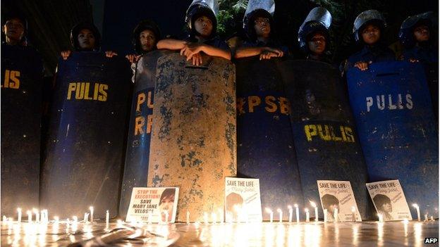 Anti-riot policemen with their shields stand next to lit candles and portraits of Filipina Mary Jane Veloso who is due for execution in Indonesia, as activists hold a vigil in front of the Indonesian embassy in Manila on 28 April 2015