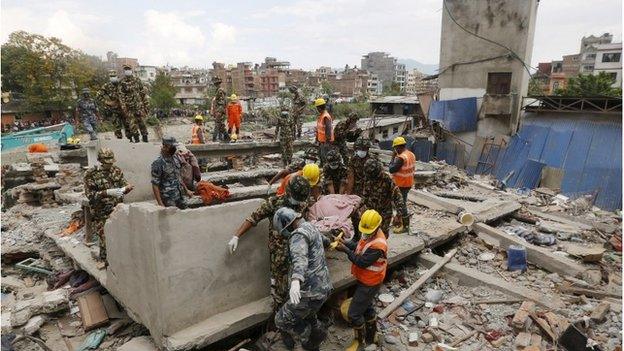 Nepali army soldiers and India's National Disaster Response Force carry a body from a collapsed house in Kathmandu