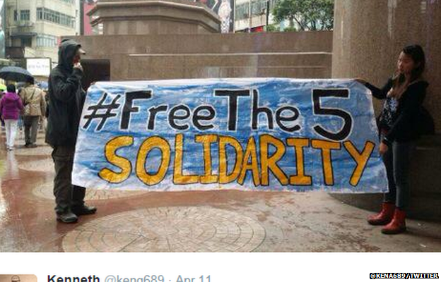 Protestors hold up a "Free The Five" banner