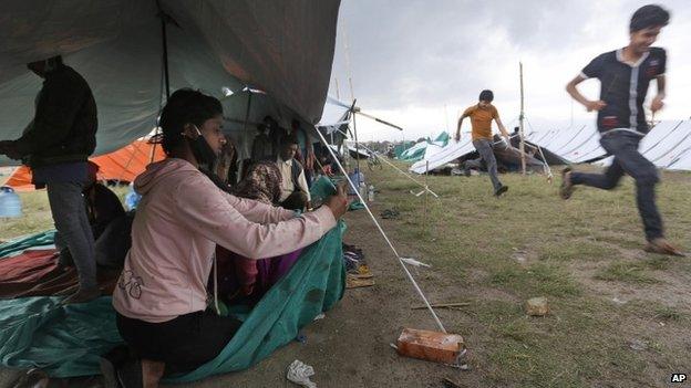 A Nepalese woman victim of an earthquake fixes her makeshift tent from a sudden rain in Kathmandu, Nepal, Tuesday, April 28, 2015.