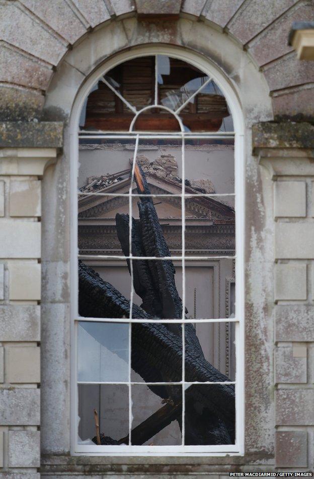 Fire damaged timbers are seen through a broken window at Clandon Park House