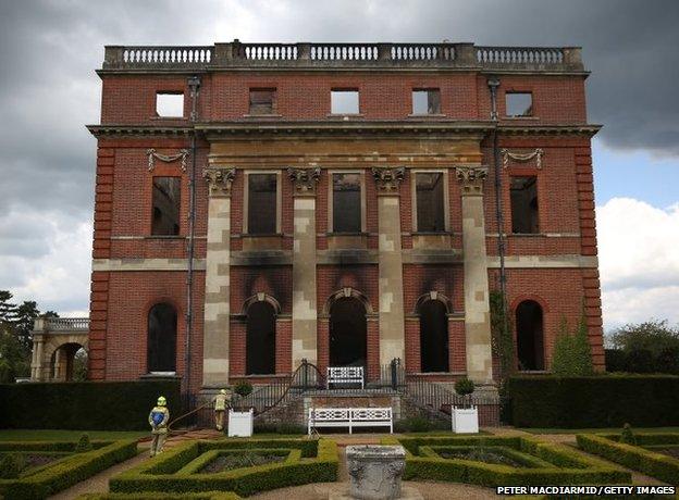 Fire brigade officers inspect the burned remains at Clandon Park House