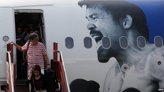 Passengers disembark from plane in Manila decorated with a picture of Manny Pacquiao