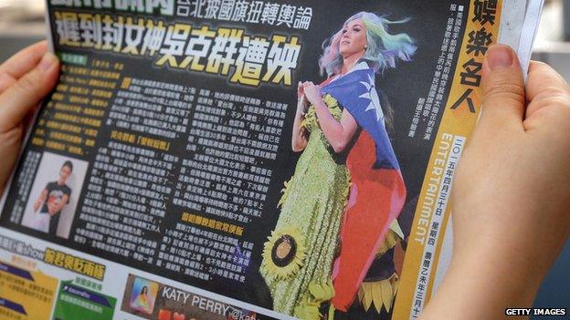 In this photo illustration taken on 30 April, 2015, a local resident reads a newspaper showing US singer Katy Perry wearing Taiwan's national flag