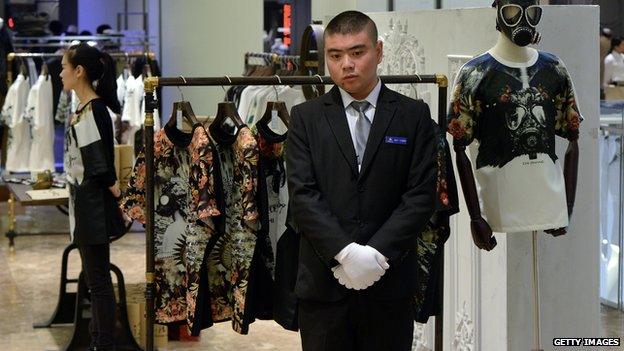 A Chinese man stands near a mannequin decorated with a gas mask at the Galeries Lafayette department store during its official opening in Beijing on 18 October, 2014