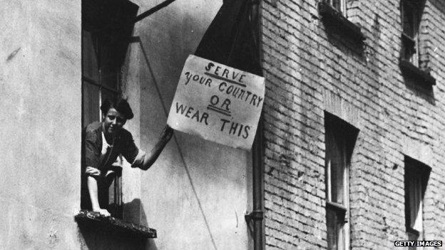 Woman holds placard which reads: "Serve your country or wear this"