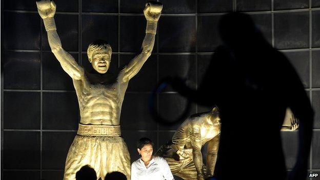 Fans of Philippine boxing superstar Manny Pacquiao pose for a picture by Pacquiao's statue at the bay side of Manila on November 26, 2010.