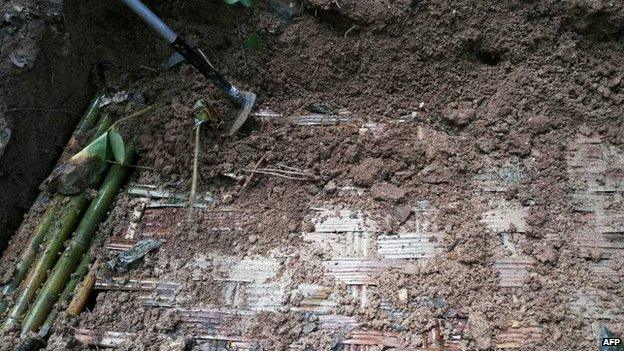 Rescue workers and forensic officials inspect the site of a mass grave at an abandoned jungle camp in the Sadao district of Thailand"s southern Songkhla province bordering Malaysia on 1 May 2015.