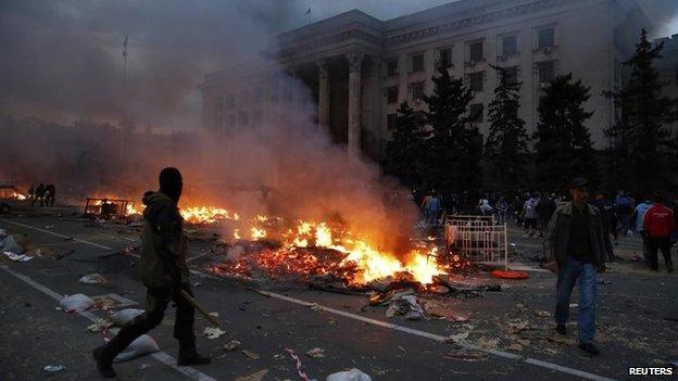 A protester walks past a burning pro-Russian tent camp near the trade union building in Odessa on 2 May 2014