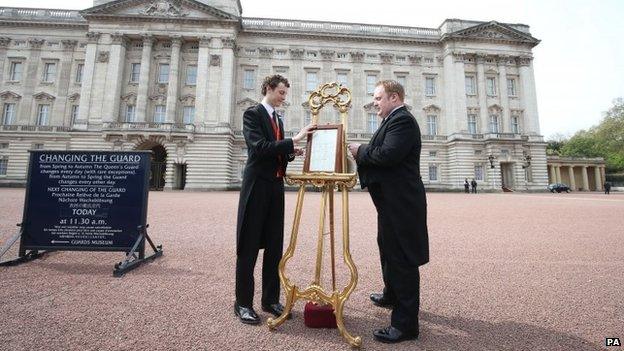 An easel is placed in the Forecourt of Buckingham Palace