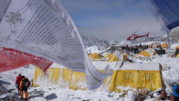 A Buddhist prayer flags flutters in the wind near tents as a rescue helicopter takes off from Everest Base Camp on 26 April 2015