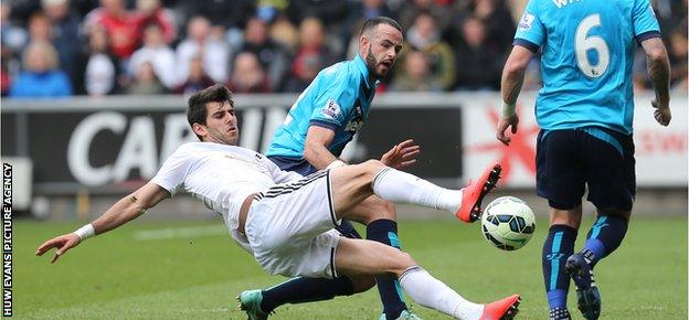 Swansea's Nelson Oliveira goes down under the challenge of Stoke's Marc Wilson, who was later sent off for two bookings