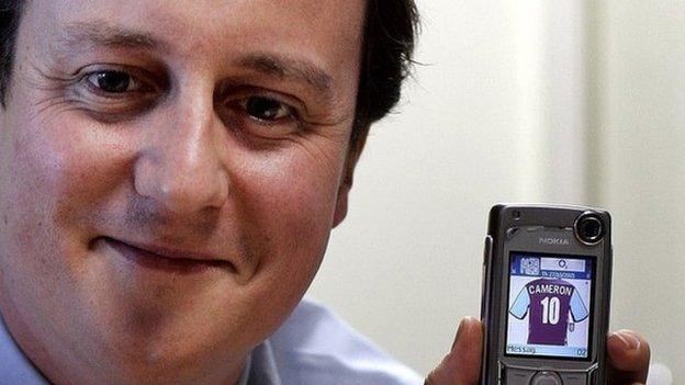 Mr Cameron, pictured in 2005, holding a phone with an image of an Aston Villa shirt with this name on it