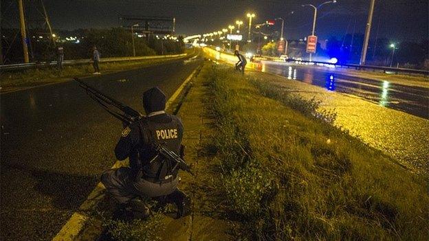 South African Policemen patrol during a standoff with looters on the National Highway in Johannesburg on 18 April 2015, as looting of foreign owned shops and xenophobic attacks escalated