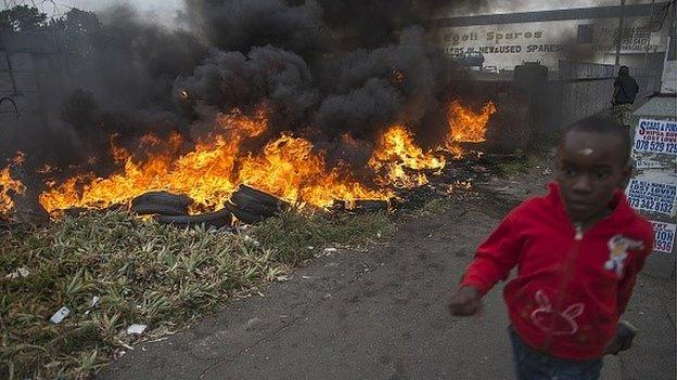 Child runs pass burning tires during the xenophic violence, on 17 April 2015 in Jeppestown area of central Johannesburg