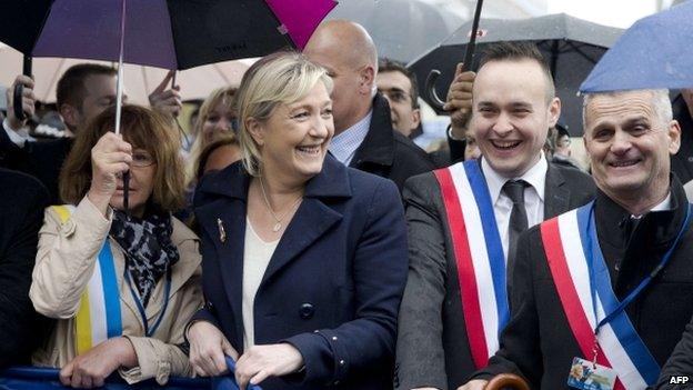 The president of French far-right party Front National (FN) Marine Le Pen (C) holds a banner as she marches during the party"s annual rally in honour of Jeanne d"Arc (Joan of Arc) on 1 May 2015 in Paris.