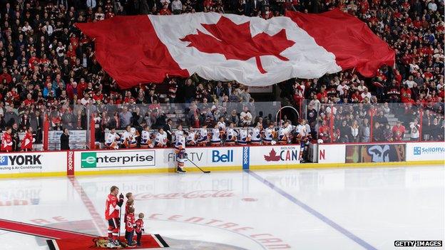 Daniel Alfredsson #11 of the Ottawa Senators and his family stand at centre ice as a Canadian flag gets passed in the crowd prior to a ceremonial puck drop in his honour during an NHL game against the New York Islanders at Canadian Tire Centre on 4 December 2014 in Ottawa, Ontario, Canada.