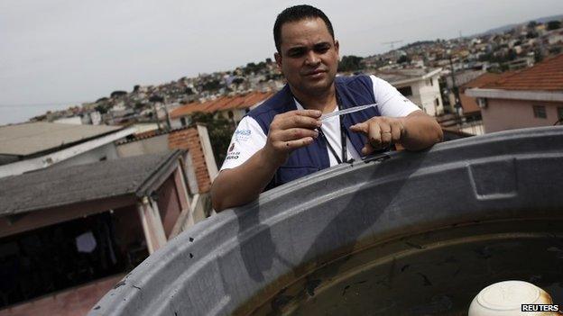 A national health official checks a water tank for mosquitoes during a house inspection