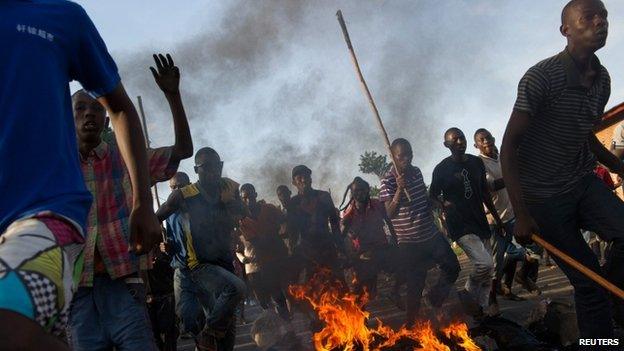 Protestors run across a fire towards police lines in the Musaga neighbourhood of Bujumbura, on May 4, 2015