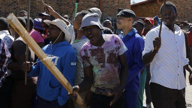 Local South African men dance and sing while carrying clubs as they call for foreign shop owners to leave the area after xenophobic violence in the area in Actonville, Johannesburg, South Africa, 16 April 2015