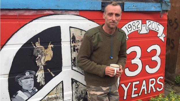 Picture of Chris Higgins against backdrop of Faslane Peace Camp