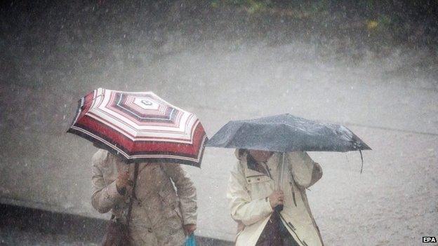 Women with umbrellas cross a flooded street during heavy rain in Hamburg, Germany, 05 May 2015