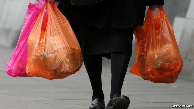 A woman carries several Sainsbury's bags of shopping