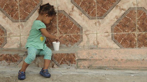 A child plays with a cup in a poor neighbourhood of Colon