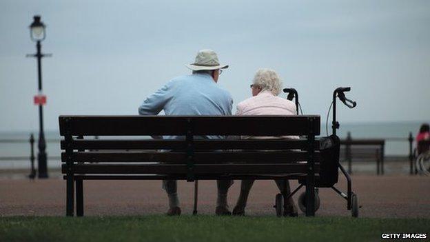 Two elderly people sit on a bench