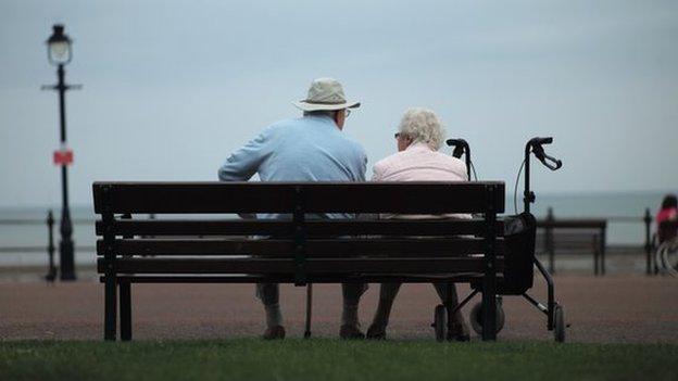 Two elderly people sit on a bench