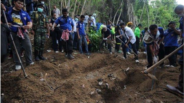 This picture taken on May 2, 2015 shows rescue workers and forensic officials digging out skeletons from shallow graves covered by bamboo at the site of a mass grave at an abandoned jungle camp in the Sadao district of Thailand's southern Songkhla province bordering Malaysia